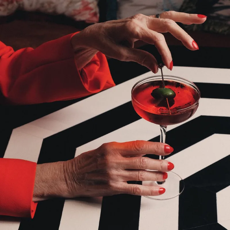 A red cocktail on a black-and-white striped table