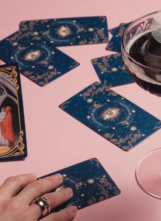 Tarot cards and a glass of red on a pink table